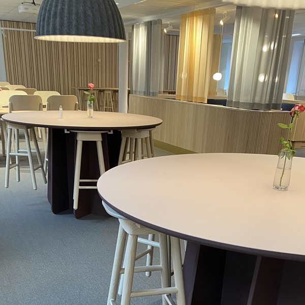 Pelarbordet Funghi med det självlåsande pelarstativet helt i trä med träpallen SitOnMe. I bakgrunden träbordet Arko och trästolen Tova-S i massiv ask