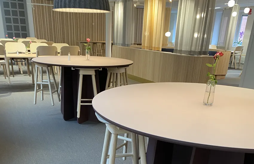 Pelarbordet Funghi med det självlåsande pelarstativet helt i trä med träpallen SitOnMe. I bakgrunden träbordet Arko och trästolen Tova-S i massiv ask