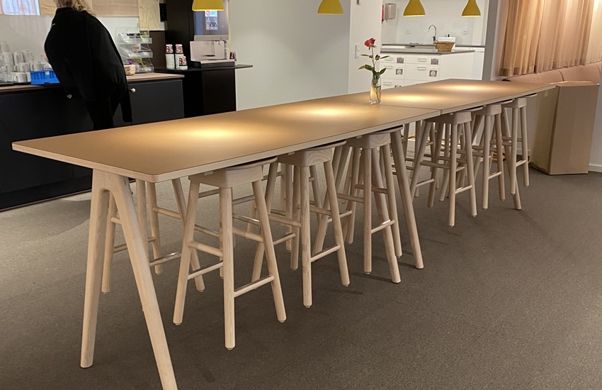 Träborden arko i höjd 900 mm i ask med desktop linoleum, möblerade på rad med upphängda träpallar SitOnMe ur Lundergs Möblers kollektion