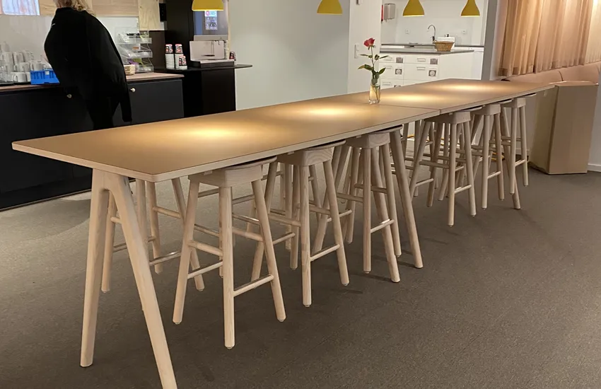 Träborden arko i höjd 900 mm i ask med desktop linoleum, möblerade på rad med upphängda träpallar SitOnMe ur Lundergs Möblers kollektion