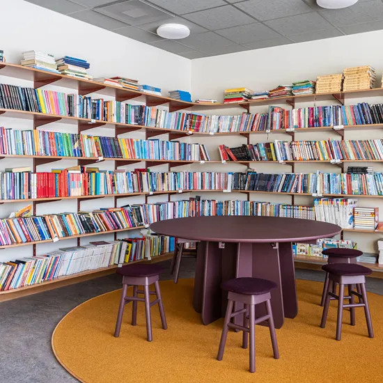 Skolbibliotekets hållbara träpelarbord Funghi i monokromt utförande Burgundy med små träpallar SitOnMe ur Lundbergs Möblers möbelkollektion