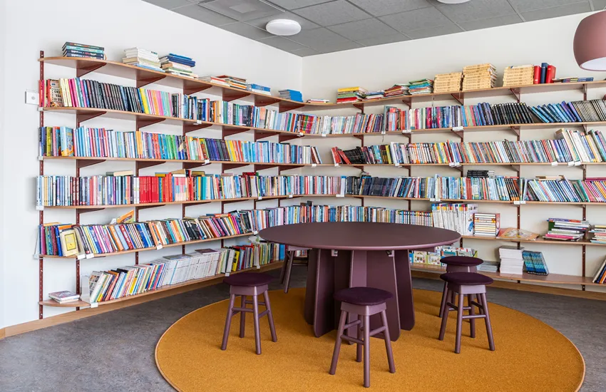 Skolbibliotekets hållbara träpelarbord Funghi i monokromt utförande Burgundy med små träpallar SitOnMe ur Lundbergs Möblers möbelkollektion